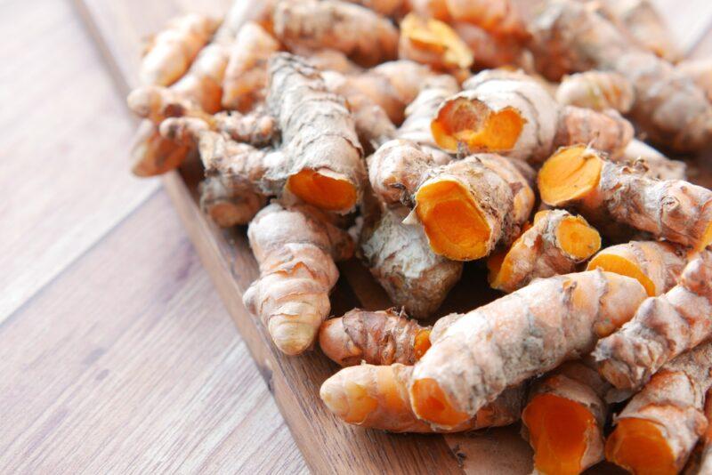 on a wooden surface is a wooden chopping board full of turmeric rhizomes