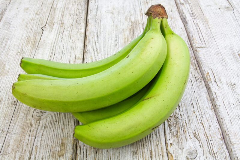 on a wooden surface is a bunch of green bananas