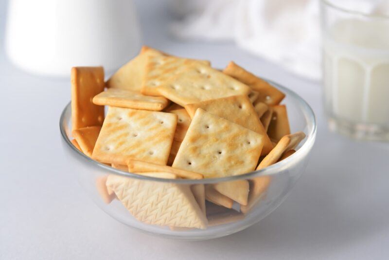 on a white surface is a clear glass bowl with unsalted crackers