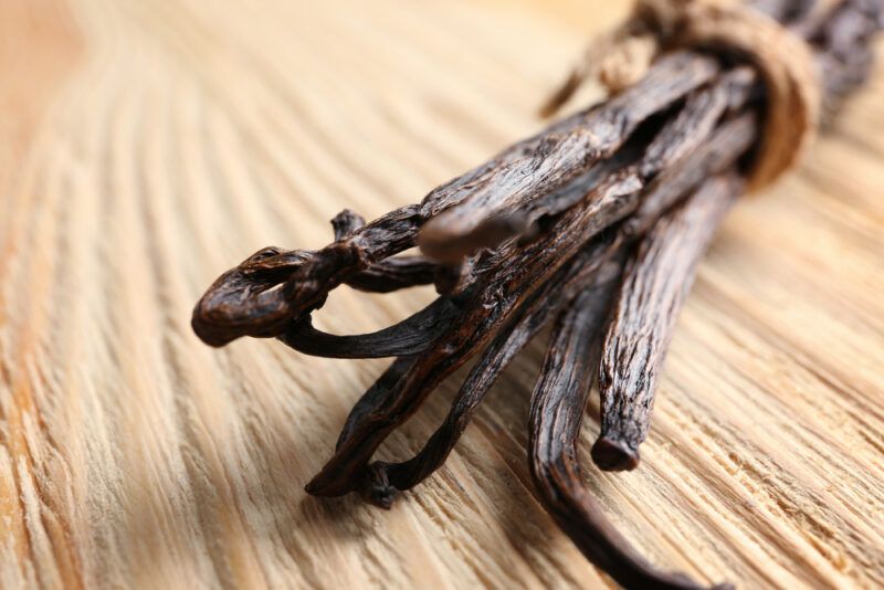 on a wooden surface are vanilla pods tied together by a brown twine