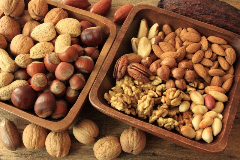 peanuts, hazel nuts, macadamia nuts in wooden bowls