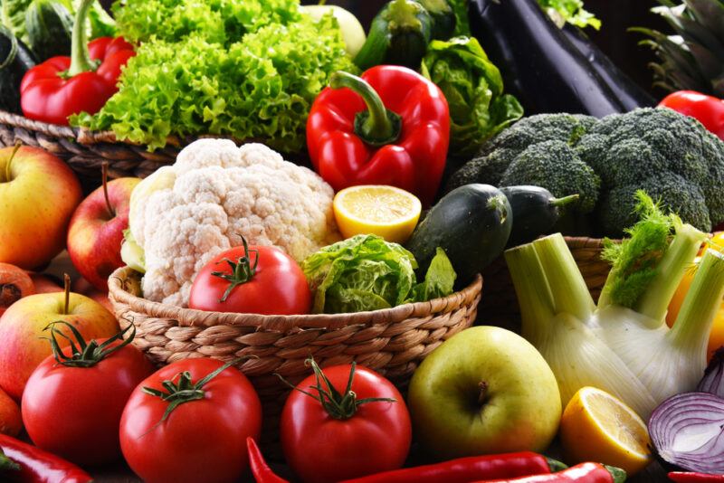 a spread of different kinds of fresh vegetables including lettuce, cauliflower, bell pepper, broccoli, eggplant, onion, lemon, cucumber, celery, chilis, and tomatoes