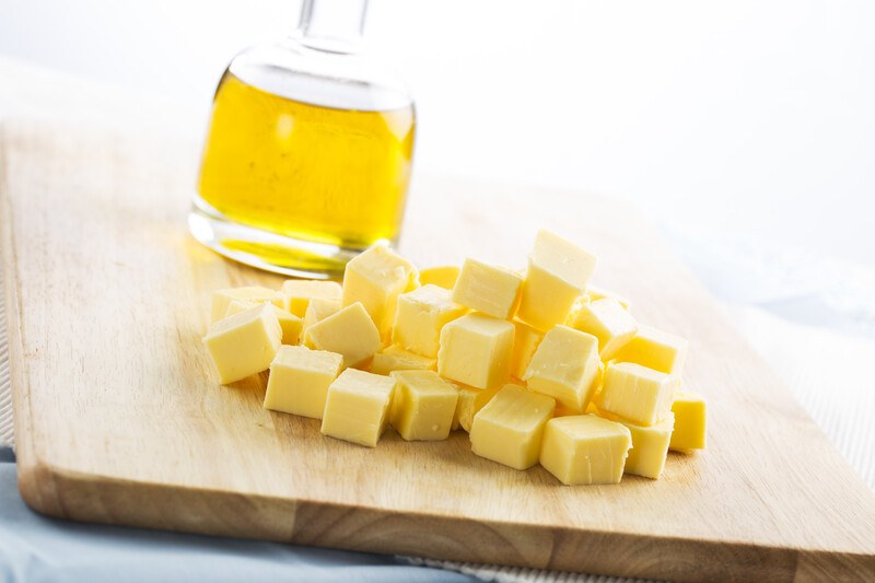 closeup image of a wooden board with cubed unsalted butter and a bottle of vegetable oil on it