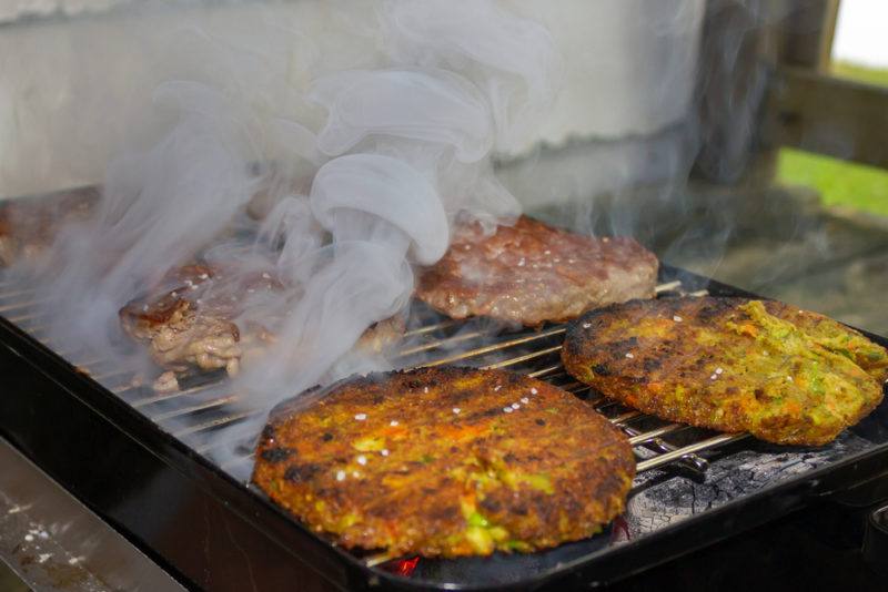 vegetarian burger patties being cooked on small charcoal grill