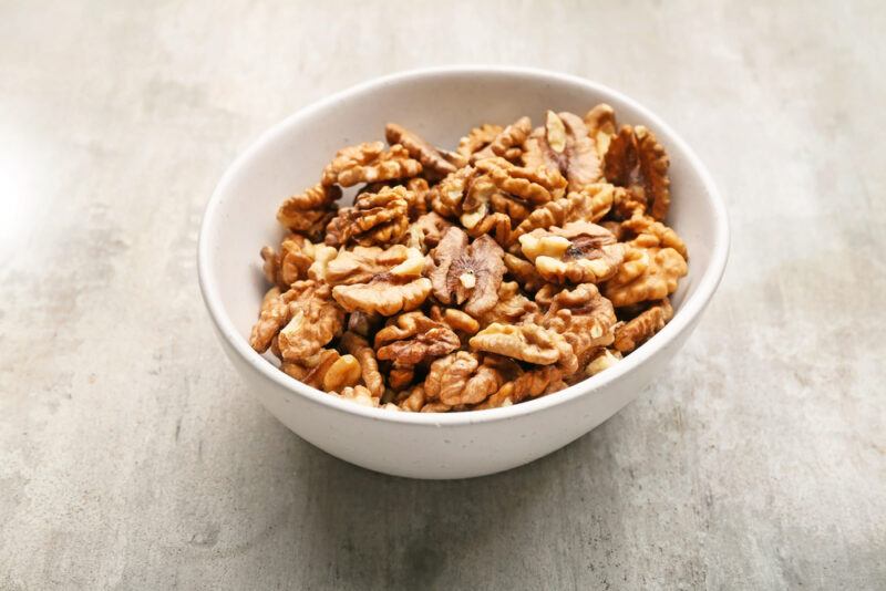 on a concrete surface is a white bowl of walnuts