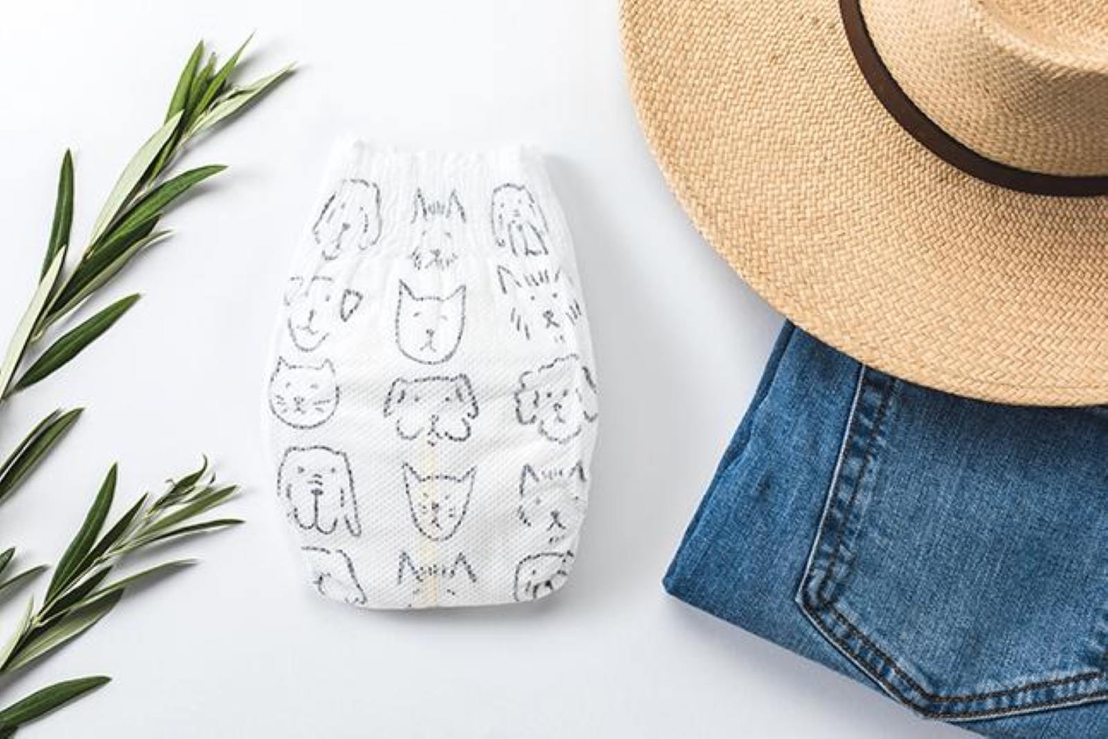 white diaper with dog and cat outlines with rosemary sprigs on the left and jeans and a hat on the right with a white background