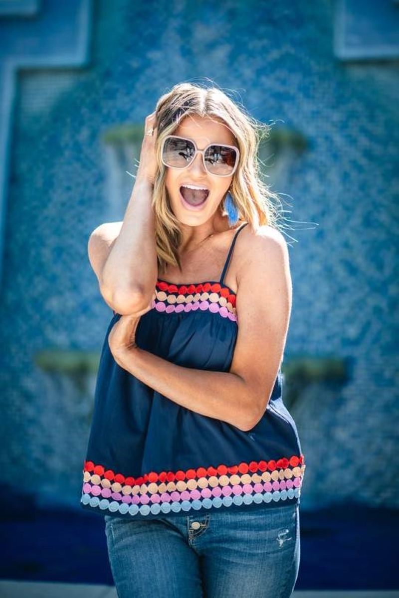 woman wearing a Blue tank top with colorful dots on the top and bottom and jeans